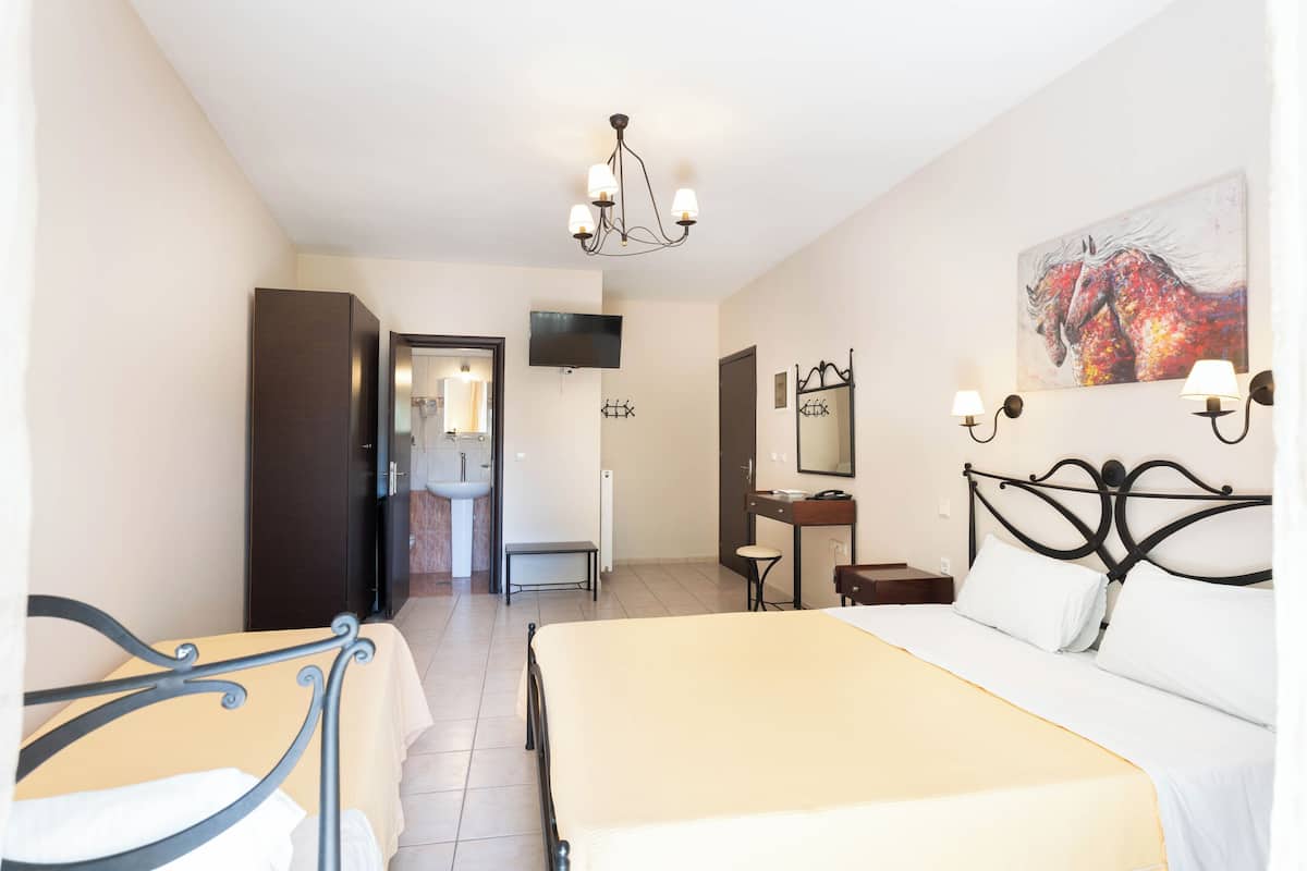 Ein Hotelzimmer mit Bett, Schreibtisch, Stuhl, Fernseher und einem durchgegangenen Tür sichtbaren Badezimmer.