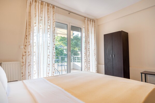 Un dormitorio con cama, un armario oscuro y un balcón con una silla.