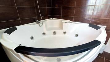 A white hot tub with a black rim, set against dark brown tiled walls.