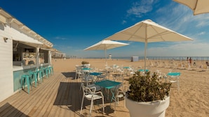 A beachside bar with outdoor seating and umbrellas, overlooking the beach. - Villa Luz Family Gourmet (Gandia)