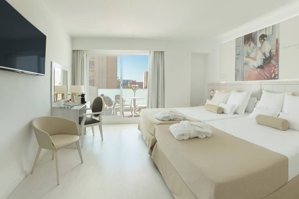 Una habitación de hotel con una cama grande, un escritorio, una silla y un televisor.