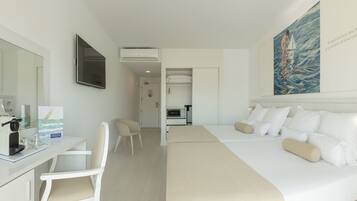 A hotel room with a bed, a desk with a coffee machine, a chair, a TV, and a painting on the wall.