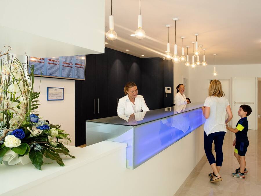 A reception area with a glass counter, a floral arrangement, and a sign with text.
