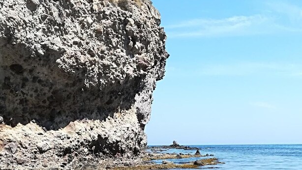 Una playa rocosa con agua cristalina y un acantilado.