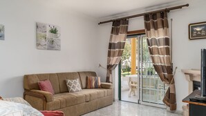 Un salon comprenant un canapé, une cheminée et une porte-fenêtre coulissante donnant sur un espace extérieur.
