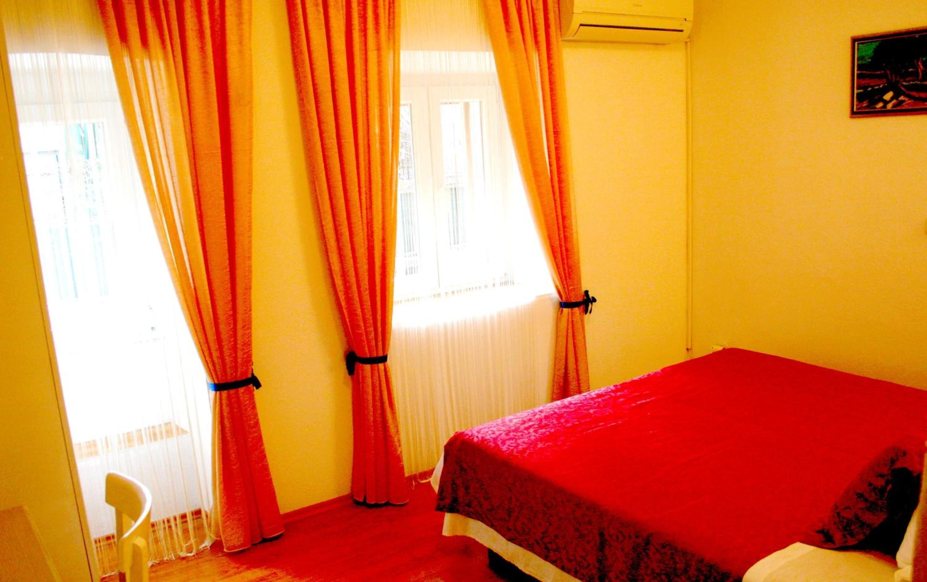 A room with a bed, curtains, a chair, and a window.