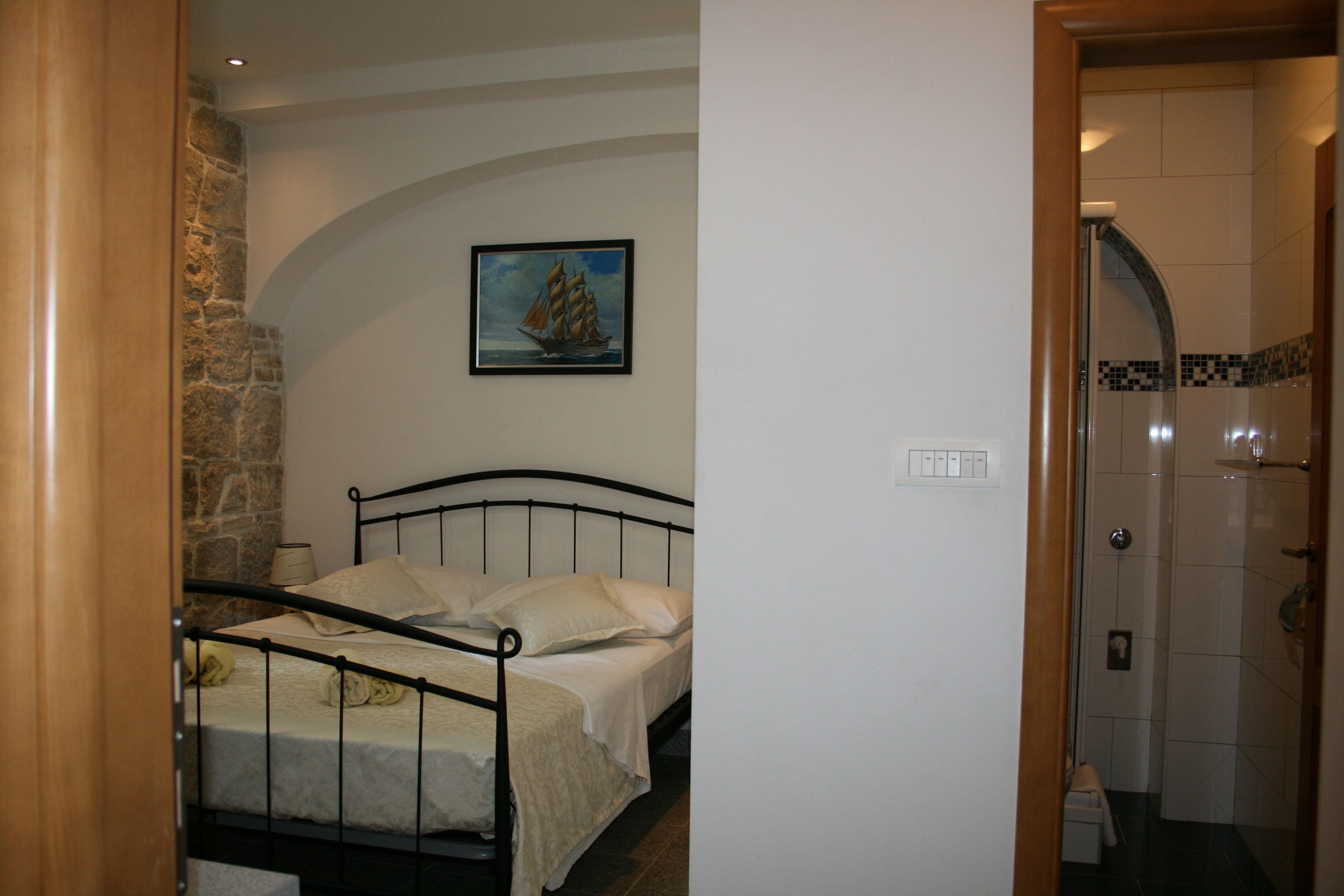 Un dormitorio con cama, un cuadro en la pared y un baño visible a través de una puerta abierta.