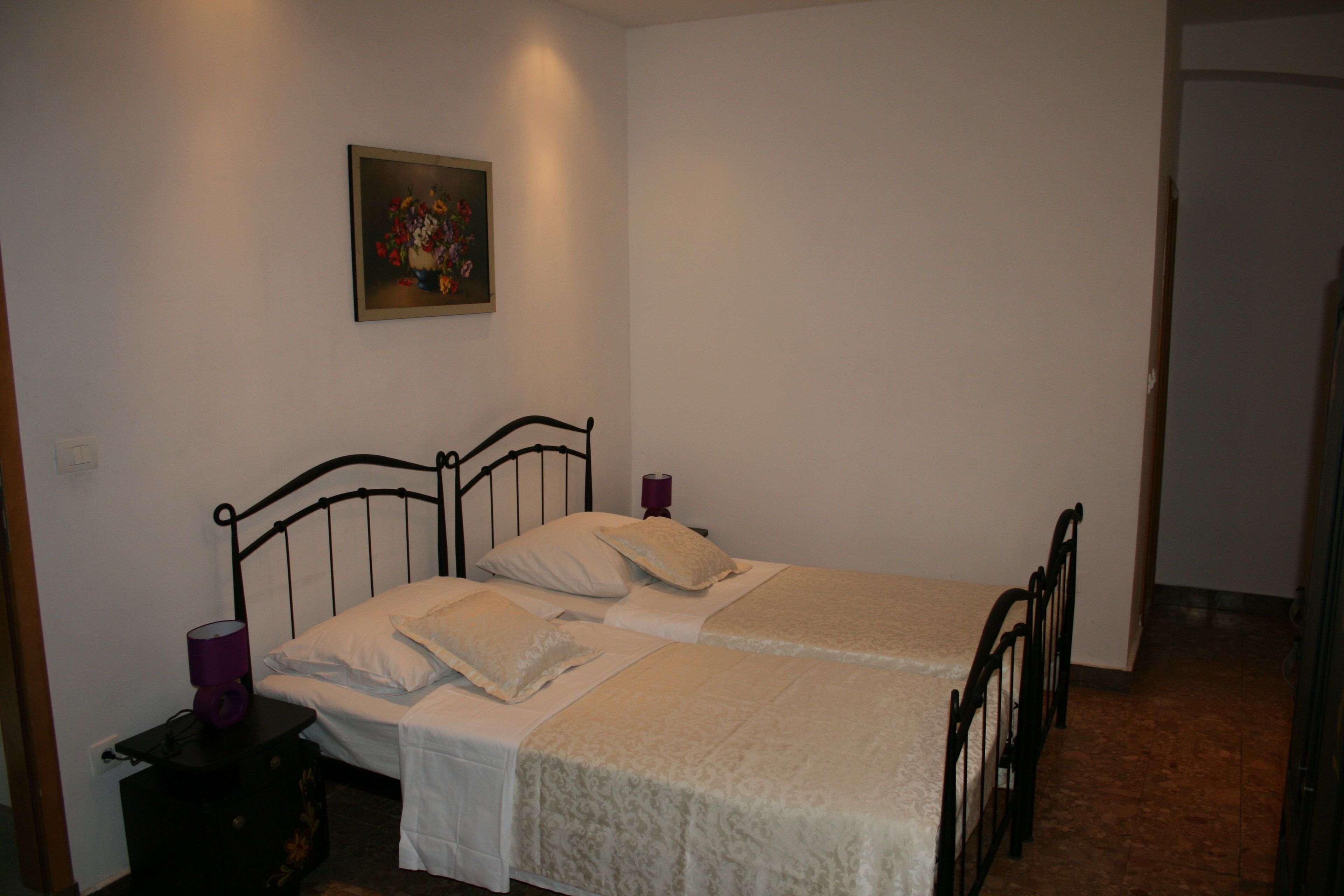 A simple bedroom with a bed, a nightstand, a lamp, and a painting on the wall.