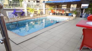 A swimming pool with tiled flooring and a few chairs and tables around it. - De Fellas Palace Hotel & Suites (Ibadan)