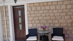 Eine Terrasse mit zwei Korbstühlen und einem kleinen runden Tisch mit einem Blumenstrauß in einer Vase.
