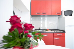 A modern kitchen with red cabinets, a white countertop, and a sink.