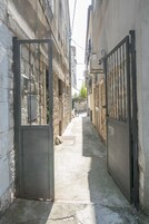 A narrow alleyway with a metal gate, stone walls, and a bicycle in the distance.