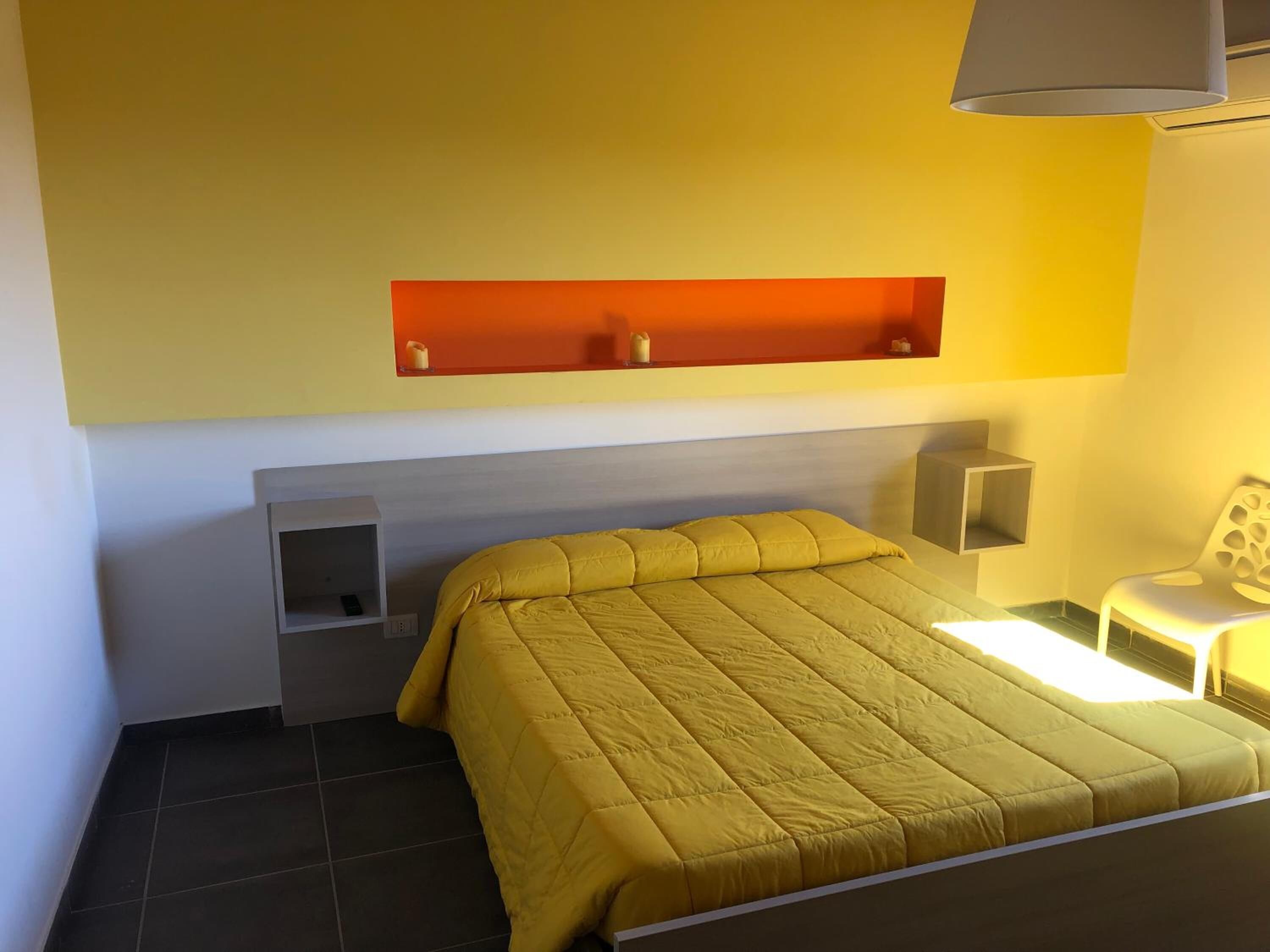 Ein Hotelzimmer mit Bett, Nachttisch, Stuhl und einer Ablage mit Dekoration.