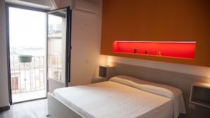 Un dormitorio con cama, estante iluminado en rojo y puerta al balcón.