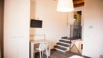 A compact living space with a dining area, a staircase, and a TV mounted on the wall.