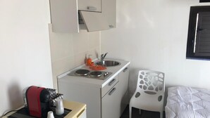 Una kitchenette compacta con estufa, lavamanos y armarios de almacenamiento.