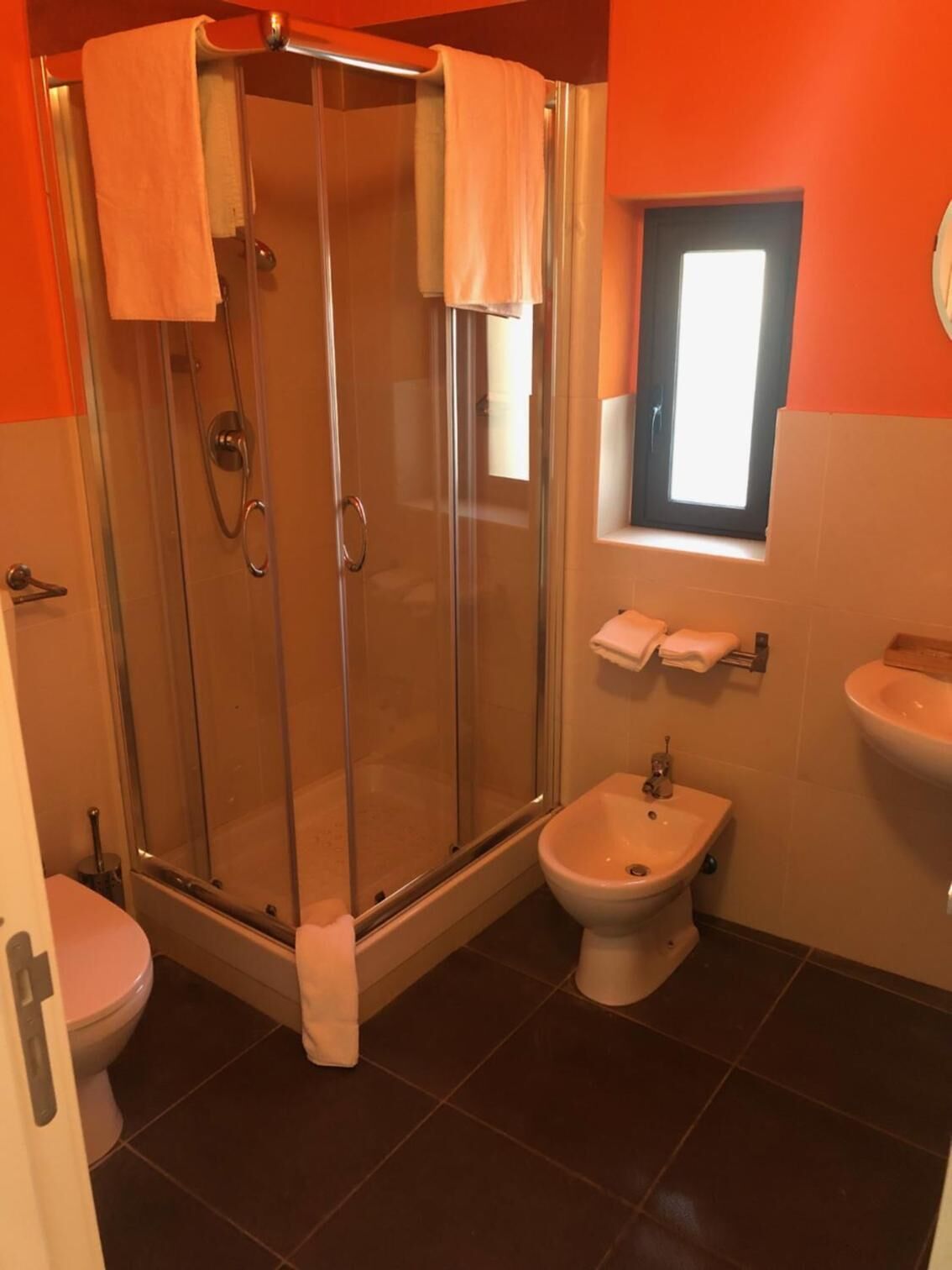 Un baño con ducha vidriada, inodoro, bidé y lavamanos.