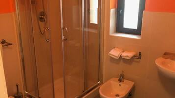Un baño con ducha vidriada, inodoro, bidé y lavamanos.