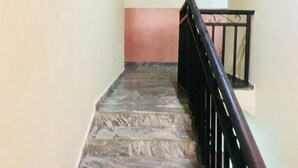 Uma escadaria com corrimão preto e parede rosa.