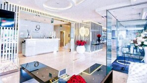 Un hall d’hôtel moderne doté d’un comptoir d’accueil, de cloisons en verre et d’un décor contemporain.