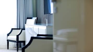 Una habitación de hotel moderna con un sofá blanco, un sillón con marco negro y un aparador blanco.