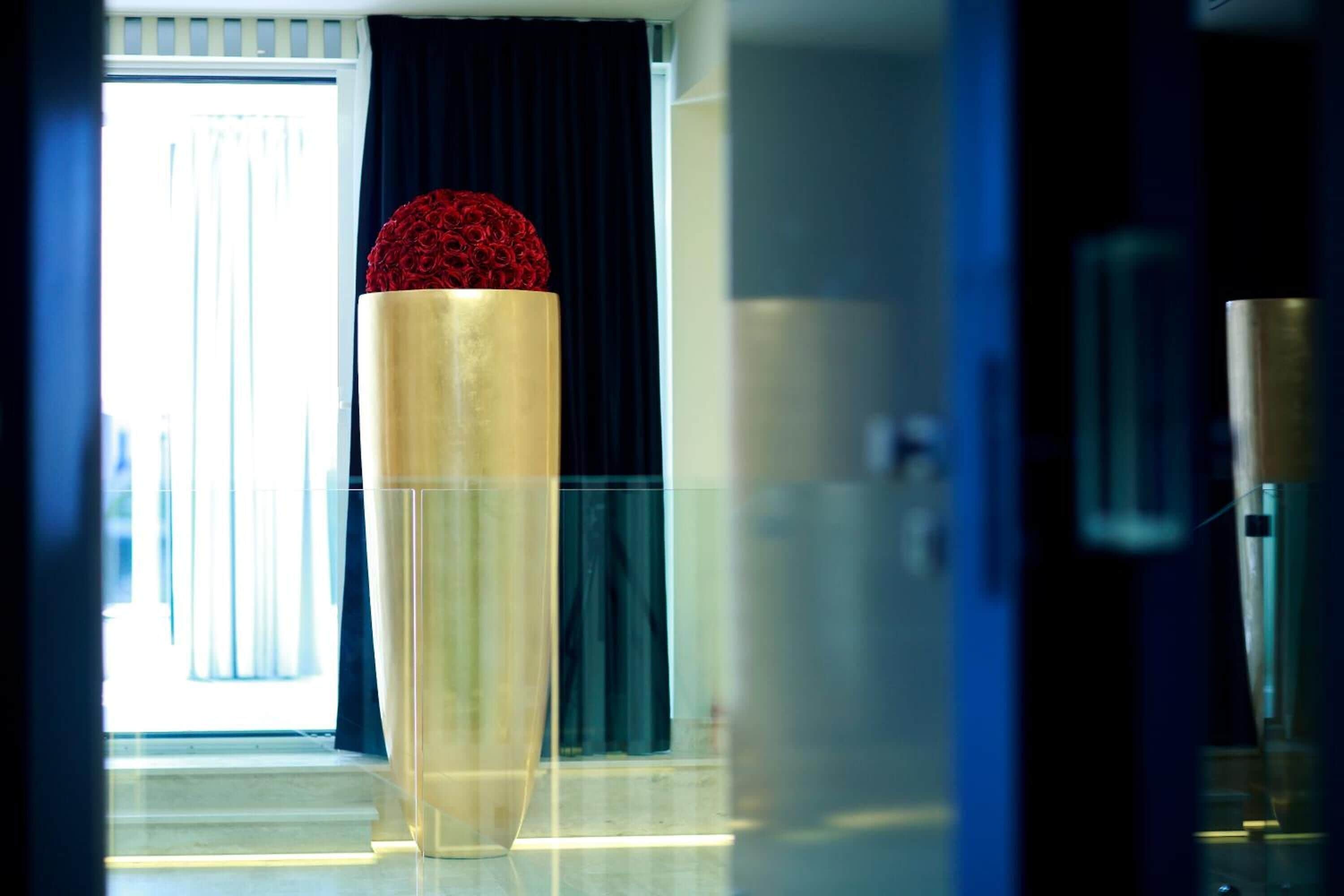 A modern hotel room with a large window, a tall cylindrical object, and a dark curtain.