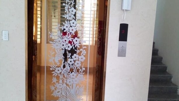 An elevator with a floral design on the door, a phone mounted on the wall, and a staircase to the right.