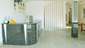 A reception area with a marble counter, a fan, a clock, and a sign that reads "Lê Tân".