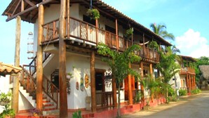 Un edificio de estilo colonial de dos pisos con balcones de madera, una escalera y un techo de tejas rojas.