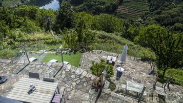 A stone patio with outdoor seating and a view of a lush landscape.