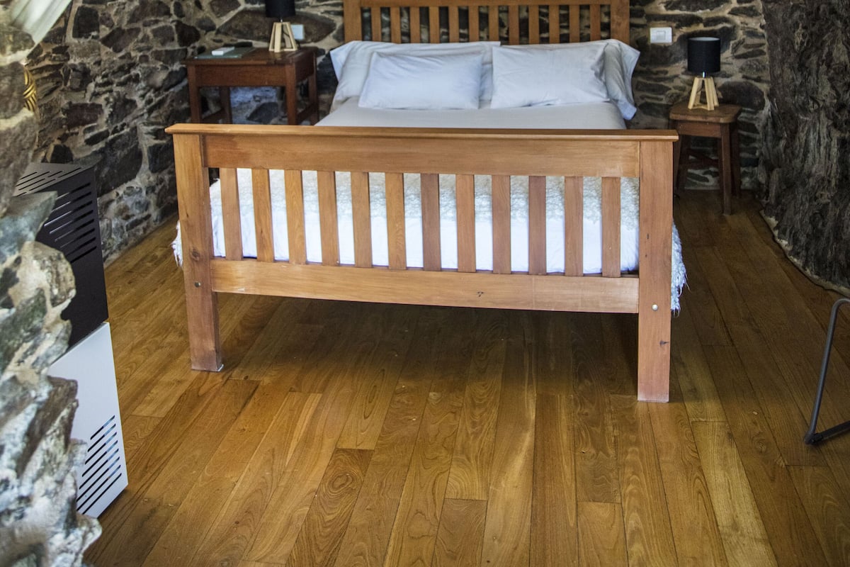 Ein Schlafzimmer mit einem hölzernen Bett, Steinwänden und einem Steinkamin.
