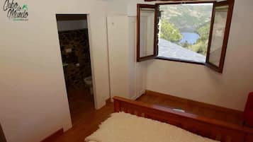 Ein Schlafzimmer mit Steinsanitärraum, einem hölzernen Bett und einem Fenster mit Seeblick.