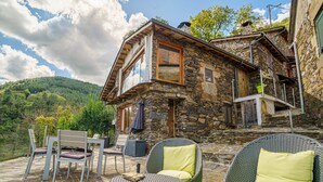 A stone house with a balcony and outdoor seating area. - Cabo Do Mundo Casa Rural (Chantada)