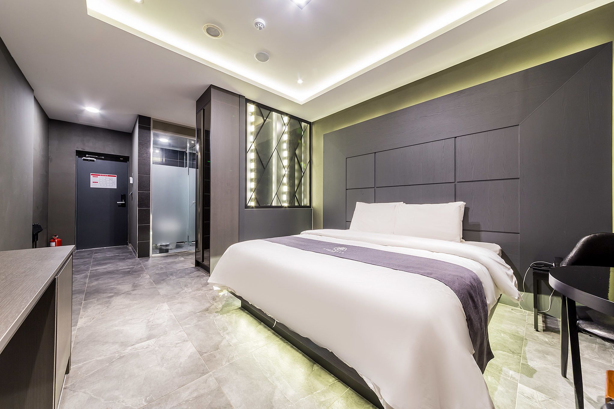 Una habitación de hotel moderna con una cama grande, mesitas de noche, un escritorio y una zona de ducha.