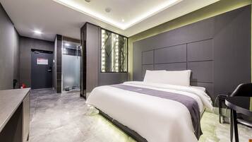 A modern hotel room with a large bed, bedside tables, a desk, and a shower area.