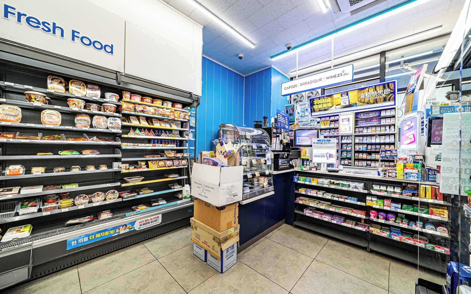 Un supermercado con estantes llenos de diversos productos alimenticios, una sección con la leyenda 'Comida Fresca' y un mostrador con material promocional.