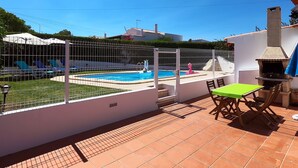 A backyard with a swimming pool, a barbecue area, and a fenced patio. - Lotus Villa, Praia da Ora - Albufeira (Albufeira)