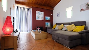 A living room with a grey sofa, wooden coffee table, and a red lamp. - Lotus Villa, Praia da Ora - Albufeira (Albufeira)