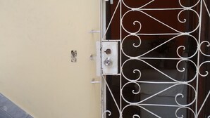 Un cancello in metallo con decorazioni elaborate, una scalinata che conduce a una porta e un piccolo tappeto all'ingresso.