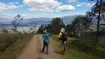 A dirt path leading to a scenic overlook with a view of a city and mountains in the distance.