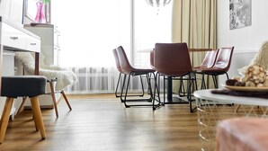A modern living room with a dining area, wooden flooring, and a large window with curtains. - 1209 Bart´s Apartment 9 (Gaschurn)