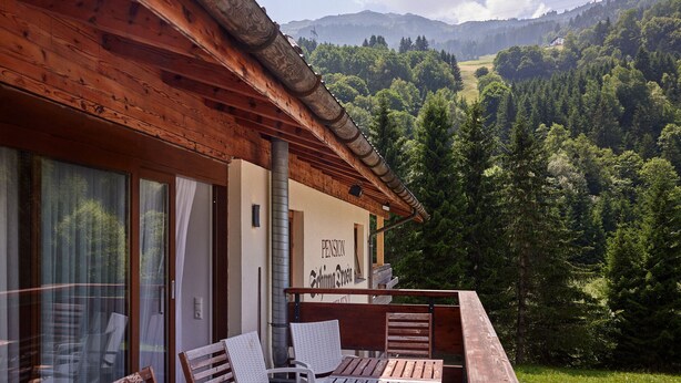 A wooden cabin with a balcony overlooking a forested valley and mountains. - 1209 Bart´s Apartment 9 (Gaschurn)