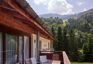 A wooden cabin with a balcony overlooking a forested valley and mountains. - 1209 Bart´s Apartment 9 (Gaschurn)