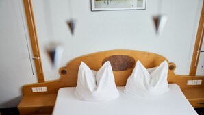 A neatly made bed with a wooden headboard, two white pillows, and a white mattress cover. - 1105 Veilchen (Gaschurn)