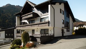 A multi-story building with a balcony, a mountain backdrop, and a clear sky. - 1105 Veilchen (Gaschurn)