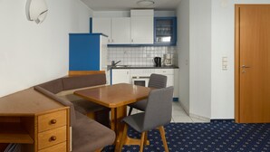 A compact kitchen with white cabinets, a blue refrigerator, and a wooden door. - 1105 Veilchen (Gaschurn)