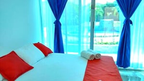 A hotel room with a bed, red and white pillows, a red bedspread, and a remote control on the bed. - Cabañas Vacacionales En Palomino Guajira (Dibulla)