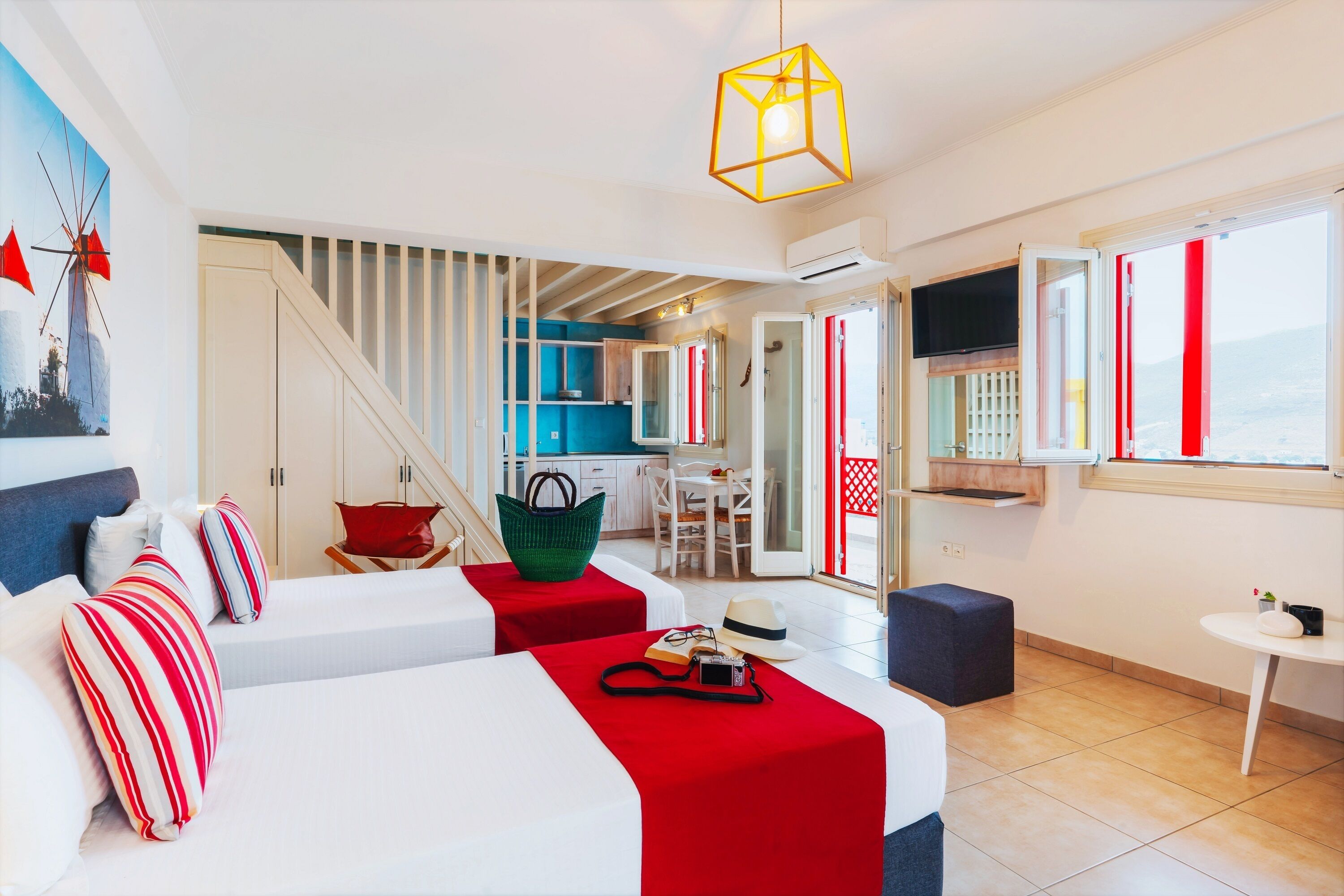 A hotel room with a bed, a desk, a chair, and a kitchen area.