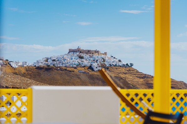 A view of a white-washed village with a castle on a hill, framed by a yellow structure. - Aelia Apartments & Suites (Astypalaia)