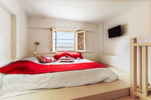 Een slaapkamer met een bed, een raam, een televisie en uitzicht op de omgeving.
